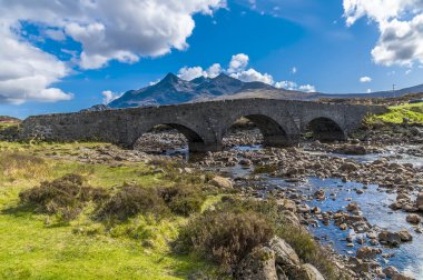 İskoçya 'nın Skye Adası' ndaki uzak Cuillin Tepeleri 'nin arka planıyla Sligachan' daki eski köprünün manzarası