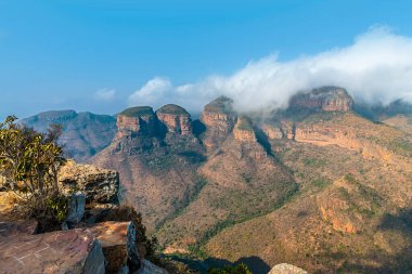 A view past a rocky outcrop on the side of Blyde River Canyon towards three Rondavels,  Mpumalanga, South Africa in Springtime