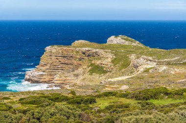 Baharda Güney Afrika, Ümit Burnu 'ndaki kayalık burnun üzerindeki deniz fenerine giden patikadan bir manzara.