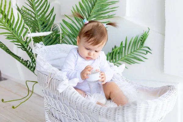 可爱的小女孩穿着白色的紧身衣坐在漂亮的婴儿车里 手里拿着一瓶牛奶 — 图库照片