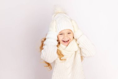 Sıcak şapkalı ve süveterli mutlu bir kız çocuğu beyaz arka planda, mesaj için yer var.