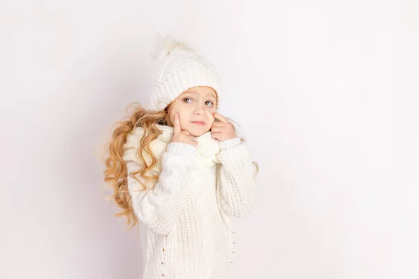 Baby Girl Touches Eyes Warm Hat Sweater White Isolated Background — стоковое фото