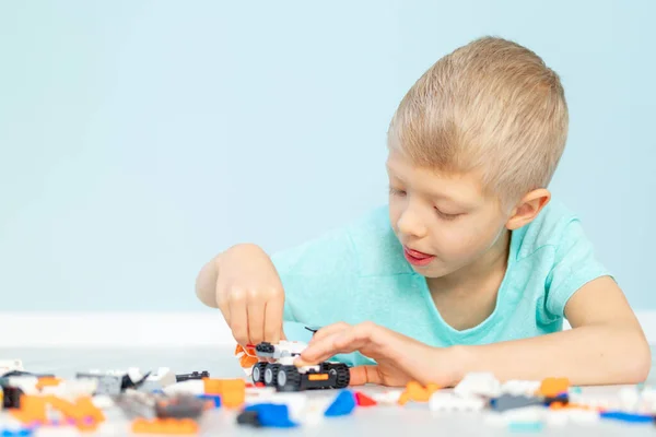 Uma Criança Brinca Com Construtor Casa Lego Fundo Azul — Fotografia de Stock