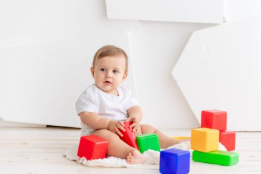 Bebek, evdeki parlak bir odada renkli küplerle oynuyor.