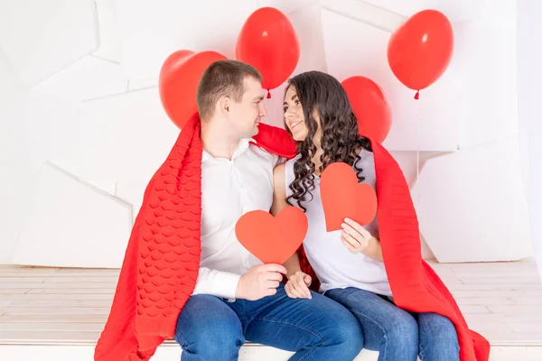 バレンタインの日恋に落ちたカップルは手に赤いハートを持ち愛情のこもった表情でお互いを見る — ストック写真