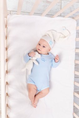 Oyuncak ayıyla beşikteki bebek yatar ya da sabah uyanır, aile ve doğum konsepti.