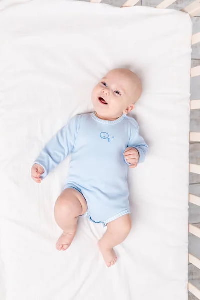 幸せな赤ちゃんはベッドの上の保育園に6ヶ月のかわいい男の子が横たわっています — ストック写真