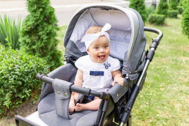 Bebek arabasındaki bebek yazın beyaz kıyafetlerle yürüyor.