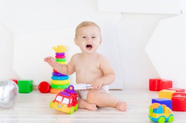 Küçük bir çocuk. Altı aylık bir çocuk. Parlak beyaz bir odada parlak oyuncaklarla oynuyor.