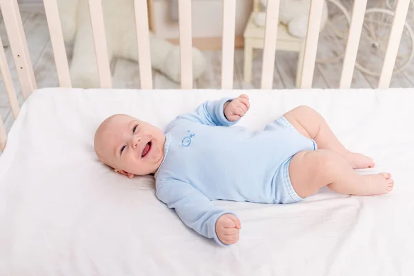 赤ちゃんはベッドの上の保育園に6ヶ月の可愛い男の子が横になって笑っています — ストック写真