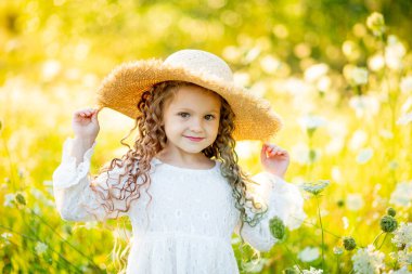 Yazın sarı bir tarlada çiçekli hasır şapkalı neşeli güzel kız.