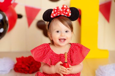 Bir yaşında, kırmızı ve sarı renkli, büyük bir ünite ve topları olan bir bebeğin doğum günü.