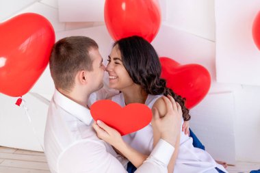 Sevgililer Günü 'nde, güzel bir kızla birlikte bir adam büyük kırmızı bir kalp taşıyan sevgi dolu bir bakışla birbirlerine bakar.