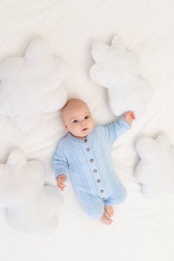 Bebek bulut yastıklarının arasında, yatakta. Çocuklar için tekstil ve yatak.