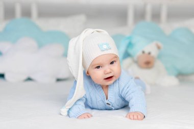 Kapüşonlu bir yatakta yatan ya da sabah uyanan bir bebek. Çocuklar için tekstil ve yatak. Oyuncak ayıyla yeni doğmuş bebek