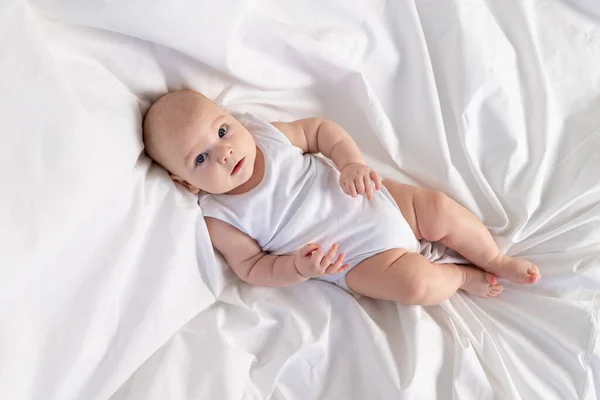 朝には白いベッドの上の子供 子供のための織物とベッドリネン 新生児が目を覚ましたか寝ようとしている — ストック写真