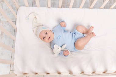 Oyuncak ayıyla beşikteki bebek yatar ya da sabah uyanır, aile ve doğum kavramı.