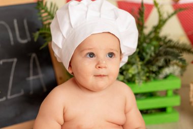 Mutfakta şef şapkası takmış küçük bir çocuğun portresi.