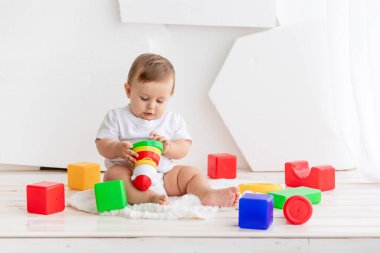 Erkek bebek evde küp ve piramitlerle oynuyor. Oyun konsepti ve çocukların gelişimi.