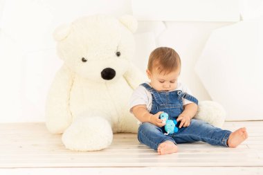 Bebek çocuk evde oyuncak ayıyla oynuyor.