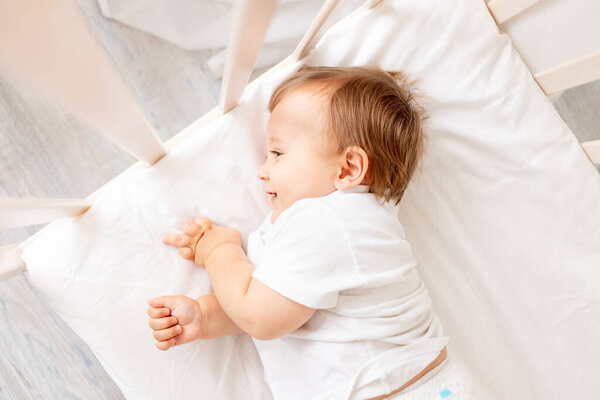 baby boy in the crib goes to bed or wakes up in the morning