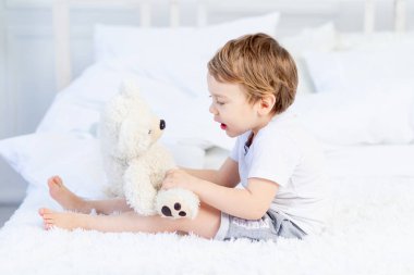 Bebek oyuncak ayıyla evde oyun oynuyor.