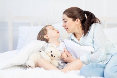 Anne ve bebeğin evde yatakta konuşması, ebeveynler ve çocuklar arasındaki ilişki kavramı.