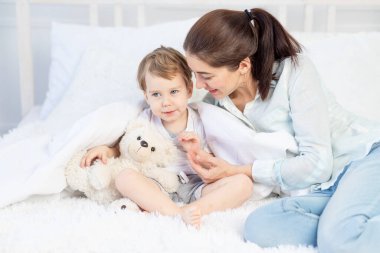 Anne evde, yatakta bebeğe sarılıyor. Aile ve çocuk kavramı, Anneler Günü.