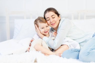 Anne evde, yatakta bebeğe sarılıyor. Aile ve çocuk kavramı, Anneler Günü.