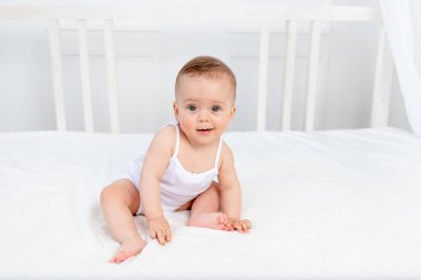 Bebek parlak bir odada, beşiğinde oturuyor.