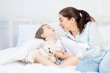 Anne ve bebeğin evde yatakta konuşması, ebeveynler ve çocuklar arasındaki ilişki kavramı.