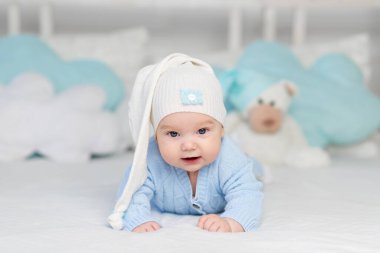 Kapüşonlu bir yatakta yatan ya da sabah uyanan bir bebek. Çocuklar için tekstil ve yatak. Oyuncak ayıyla yeni doğmuş bebek