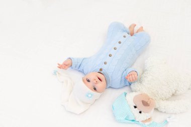 Kapüşonlu bir yatakta yatan ya da sabah uyanan bir bebek. Çocuklar için tekstil ve yatak. Oyuncak ayıyla yeni doğmuş bebek