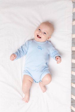 Mutlu bebek beşiğinde yatıyor, altı aylık küçük tatlı oğlan yatağında yatıyor.