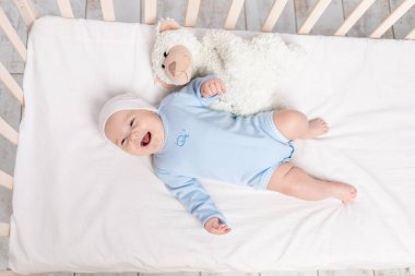 Oyuncak ayı, çocuk ve doğum konseptiyle beşikteki mutlu erkek bebek.