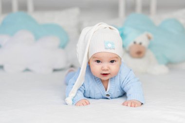 Kapüşonlu bir yatakta yatan ya da sabah uyanan bir bebek. Çocuklar için tekstil ve yatak. Oyuncak ayıyla yeni doğmuş bebek