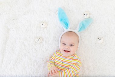 Kafasında tavşan kulağı olan bebek yumurtalarla yatıyor, sevimli, komik, gülümseyen bir bebek. Paskalya konsepti.