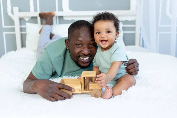 Gülümseyen Afrikalı Amerikalı Baba Küçük Oğlu Evde Yatakta Oyuncak Arabayla — Stok fotoğraf