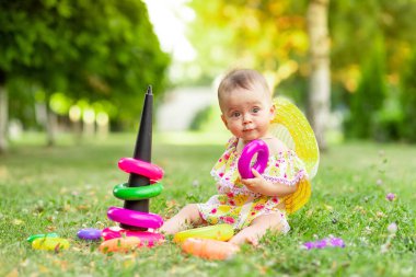 Küçük bebek yazın yeşil çimlerin üzerinde bir piramitle oynuyor.