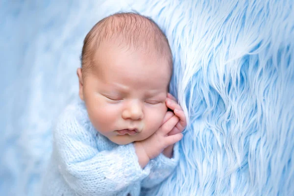 图片上的新生儿躺在蓝色的背景上睡得很香 双手交叉在脸颊下 健康的婴儿睡着了 — 图库照片