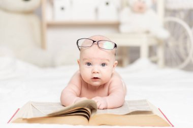 Bebek kitabı okuyor ya da çocuk odası, öğrenme ve geliştirme konseptine bakıyor.