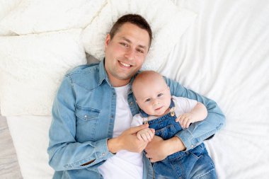 Mutlu bir baba ve küçük oğlu yatakta uzanıyor ve eğleniyor. Babalar günü ya da babalık kavramı.