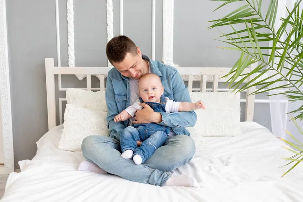 dad with a baby in his arms at home on the bed, happy fatherhood or father\'s day