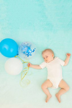 Mavi arka planda bir erkek bebek uyuyor ve rüyasında balonlarla uçuyor, mesaj atmak için yer var.