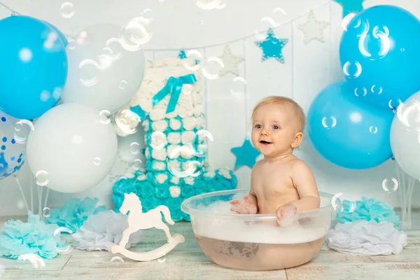 Erkek bebek sabun köpüğü ve köpükle banyo yapar şenlikli bir doğum günü dekorunda Bir yaşında, balonlu, tatilli ve dekorlu