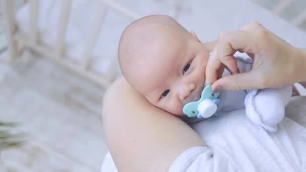 Mom cradles and calms the capricious baby in her arms with a pacifier, the newborn falls asleep — Stock Video