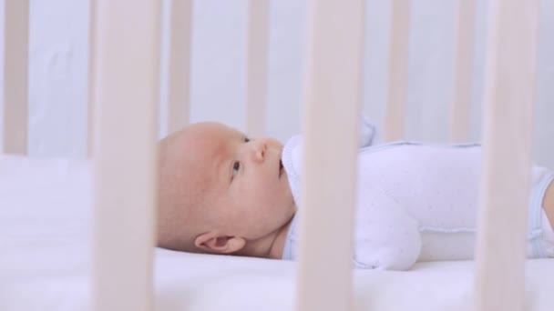 A newborn baby lies in a crib and plays with pens, a healthy baby at home — Stock Video