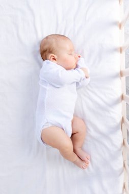 Yeni doğmuş bir bebeğin, yatak odasında pamuklu bir yatakta sağlıklı bir şekilde uyuması.