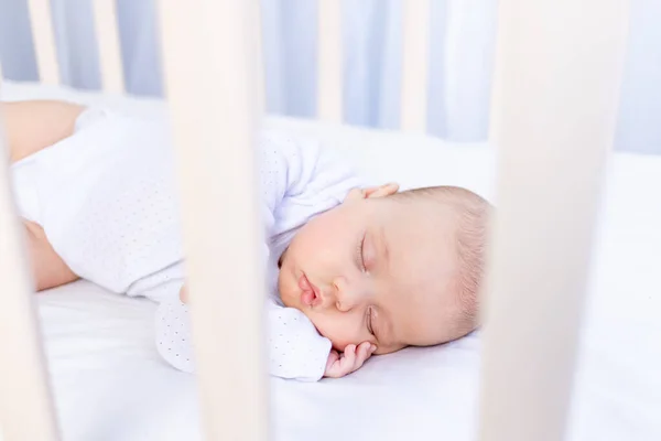 Healthy sleep of a newborn baby in a crib in the bedroom on a cotton bed, portrait — Stock Photo, Image