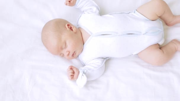 Cute little newborn baby boy sleeps in the nursery on a white cotton bed at home — Stock Video